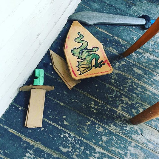 a broken cardboard sword on a peeling paint porch